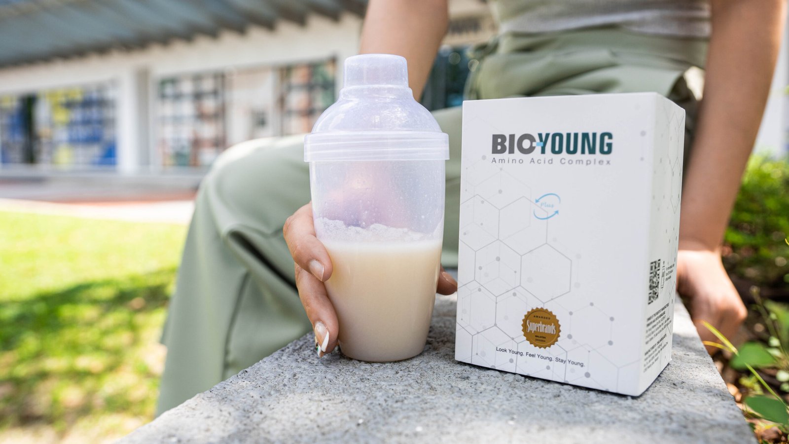 Woman holding a drink prepared with Bio Young amino acid supplement outdoors